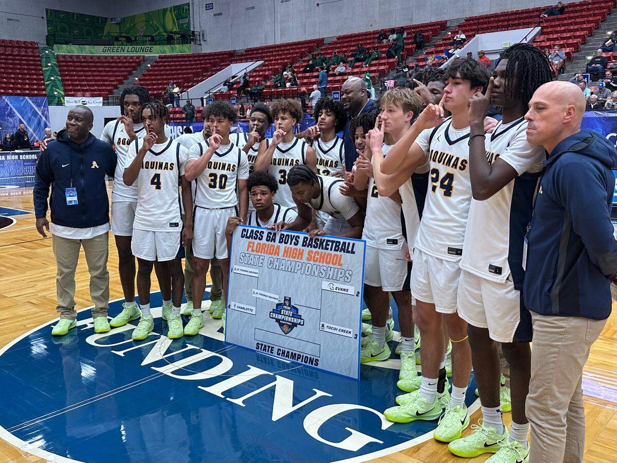 St. Thomas Aquinas’ boys’ basketball players and coaches celebrate after the Raiders beat Punta Gorda Charlotte on Thursday in a Class 6A state semifinal at the RP Funding Center in Lakeland, Fla.