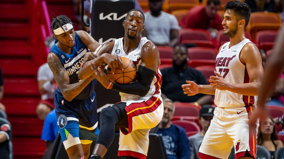Bam Adebayo (centro) lucha por un rebote con el escolta de los Timberwolves, P.J. Dozier (izq.), ante la mirada de su compañero de equipo Omer Yurtseven, en el partido celebrado el 4 de octubre de 2022 en el FTX Arena de Miami.