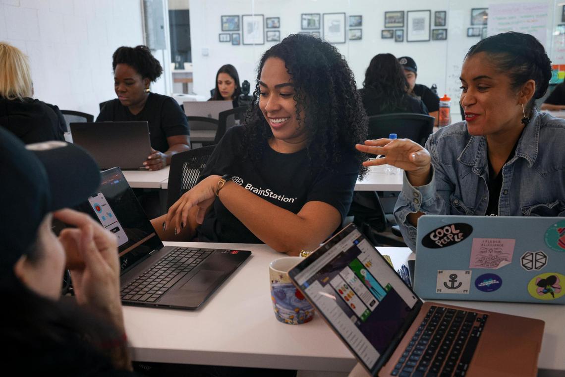 Laura Merino, center, and Daphne Essiet discuss their project during class at BrainStation on Wednesday, March 8, 2023, in Wynwood. BrainStation teaches coding, software engineering, and digital skills training.