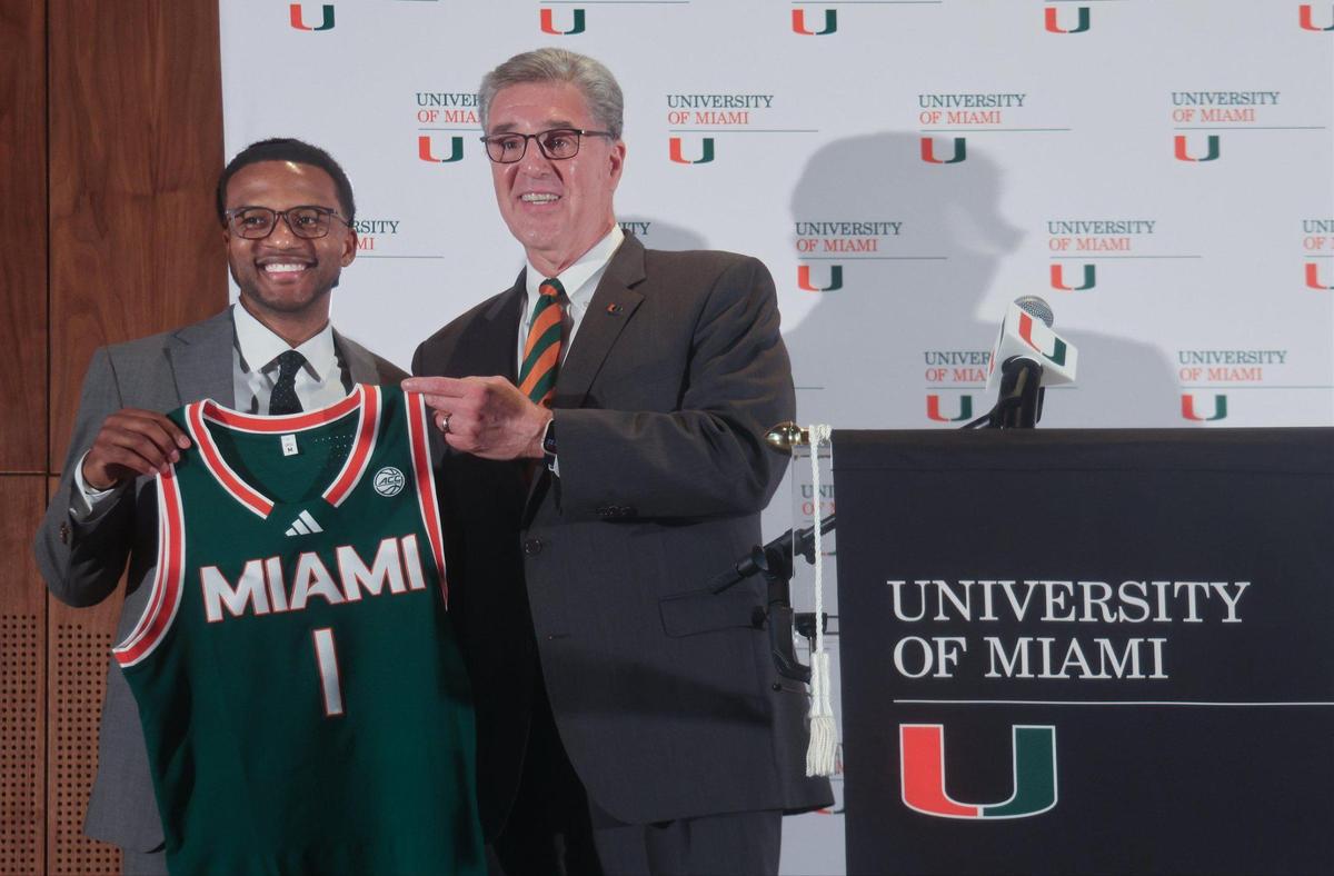Jai Lucas, left, holds his basketball jersey alongside UM athletic director Dan Radakovich on Monday during the news conference at the Lakeside Auditorium on campus.