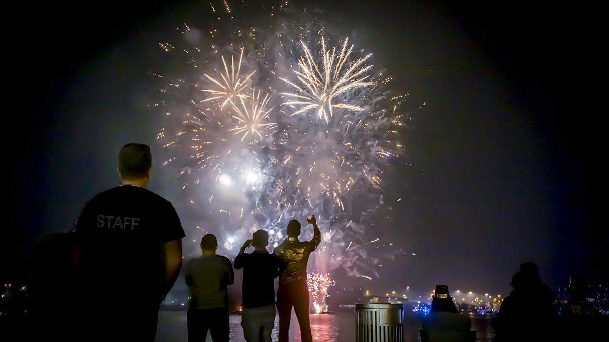 People pause to look at fireworks from different boats in Biscayne Bay during the New Year Celebration in Bayfront Park.