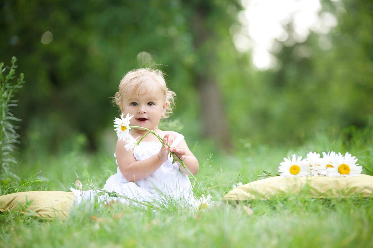 baby girl playing with daisies