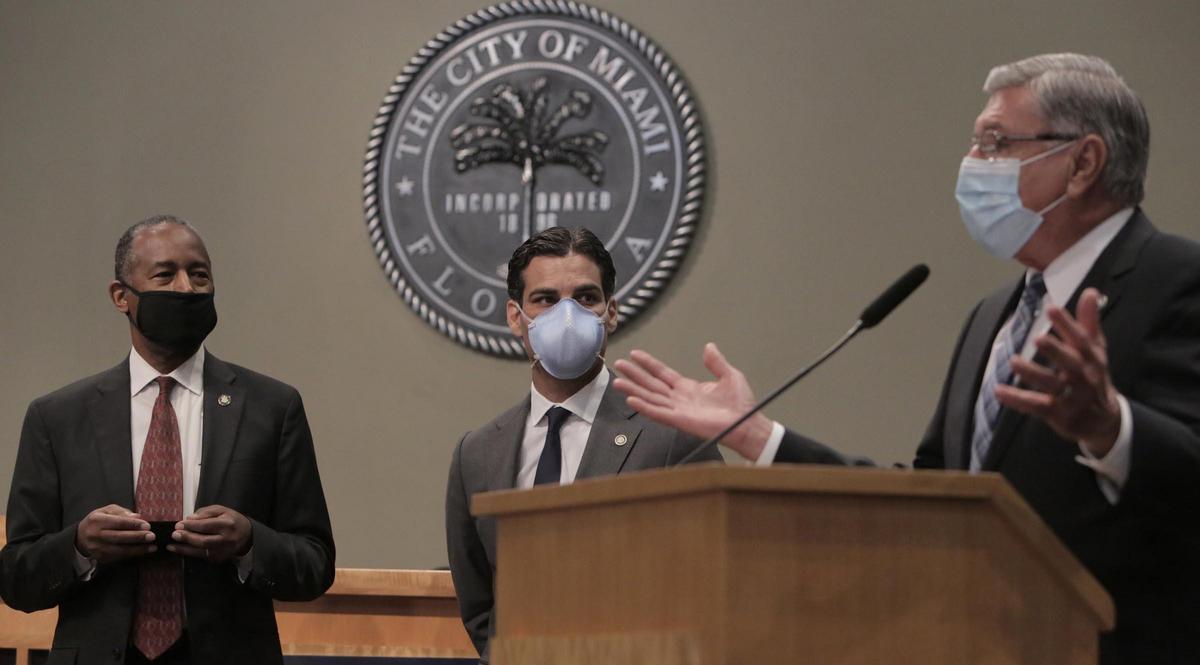 Miami City Commissioner Manolo Reyes (right) speaks as HUD Secretary Ben Carson, (left) and Miami City Mayor Francis X. Suarez (center) listen during a press conference at Miami City Hall.