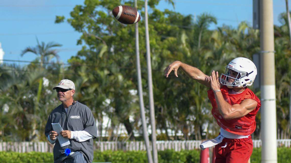 Cardinal Gibbons quarterback Dylan Rizk (right) throws during a drill while coach Matt DuBuc (left) watches on Monday, Aug. 1, 2021, at Cardinal Gibbons High School in Fort Lauderdale, Florida.