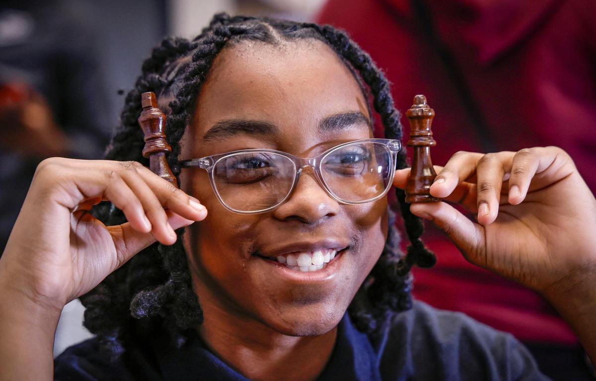 Journey White, 13, holds up the king and queen chess piece while playing with fellow students at Urgent Academy Middle School. Krisanne Stewart, director of education, says when the students play chess they develop perseverance and logical reasoning.