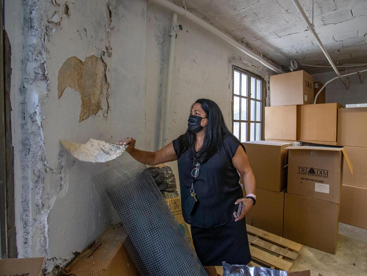Former Chief Judge for Miami-Dade, Bertila Soto, peels paint off the water-damaged walls on the 24th floor of the Miami-Dade County Courthouse on July 29, 2021. The historic courthouse is at 73 West Flagler St. in Miami.