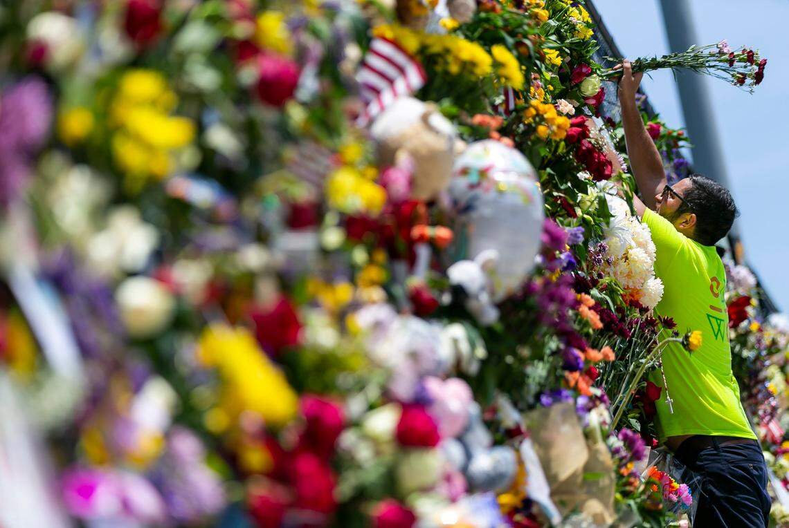 Leo Soto places flowers at the Surfside Wall of Hope & Memorial as rescue teams continue their recovery mission at the collapsed Champlain Towers South Condo building in Surfside, Florida on Friday, July 9, 2021. The memorial has grown since it was first created shortly after the collapse.