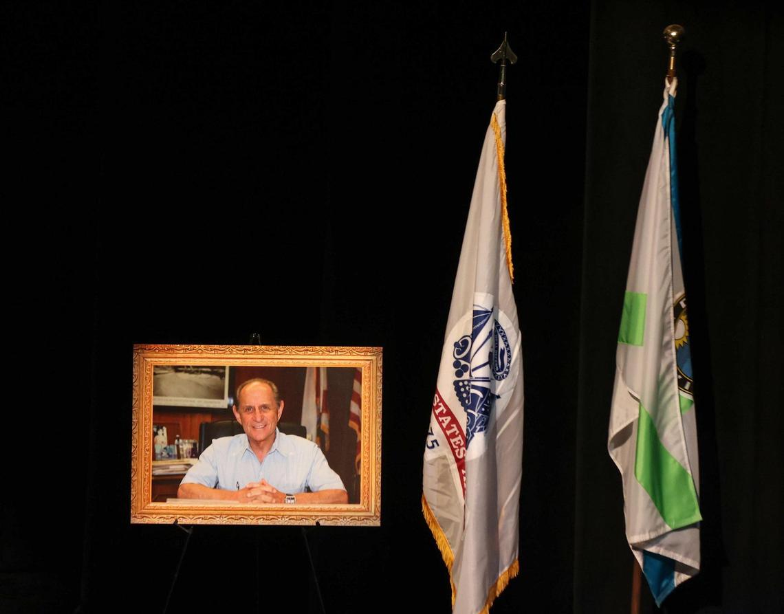 A photograph of Harvey Ruvin, the longtime Miami-Dade County Clerk of the Courts, is displayed near two flags during his celebration of life service on Thursday, Jan. 5, 2023.