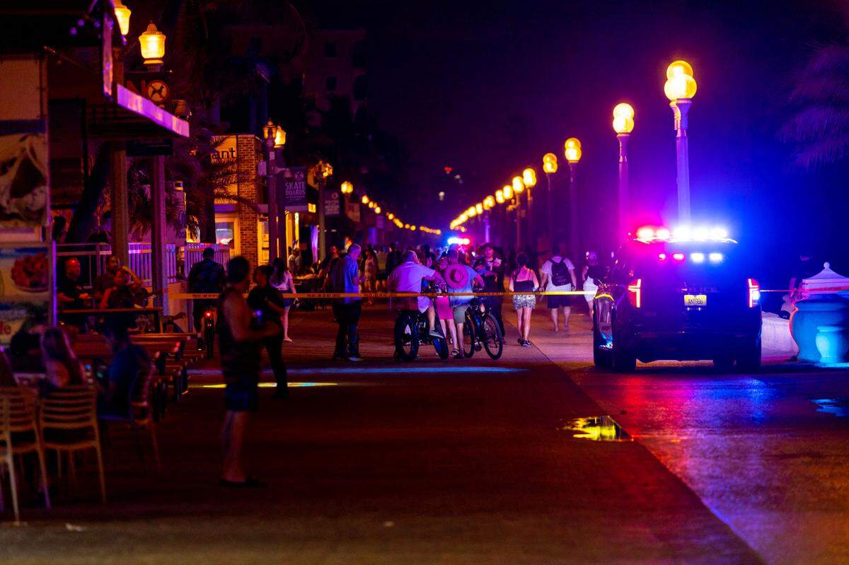 Pedestrians and bicyclist move around a Hollywood Police Car as it sits parked on the 1214 block of North Broadwalk near Nick’s Bar and Grill after police responded to reports of multiple people shot during Memorial Day weekend at Hollywood, Florida, on Monday, May 29, 2023.