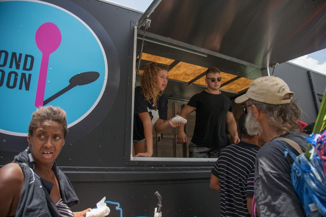 From the Second Spoon food truck, University of Miami student athletes Hannah Marwede, left, and Michael Parrot give out food and water in Overtown on Saturday, July 7, 2018.