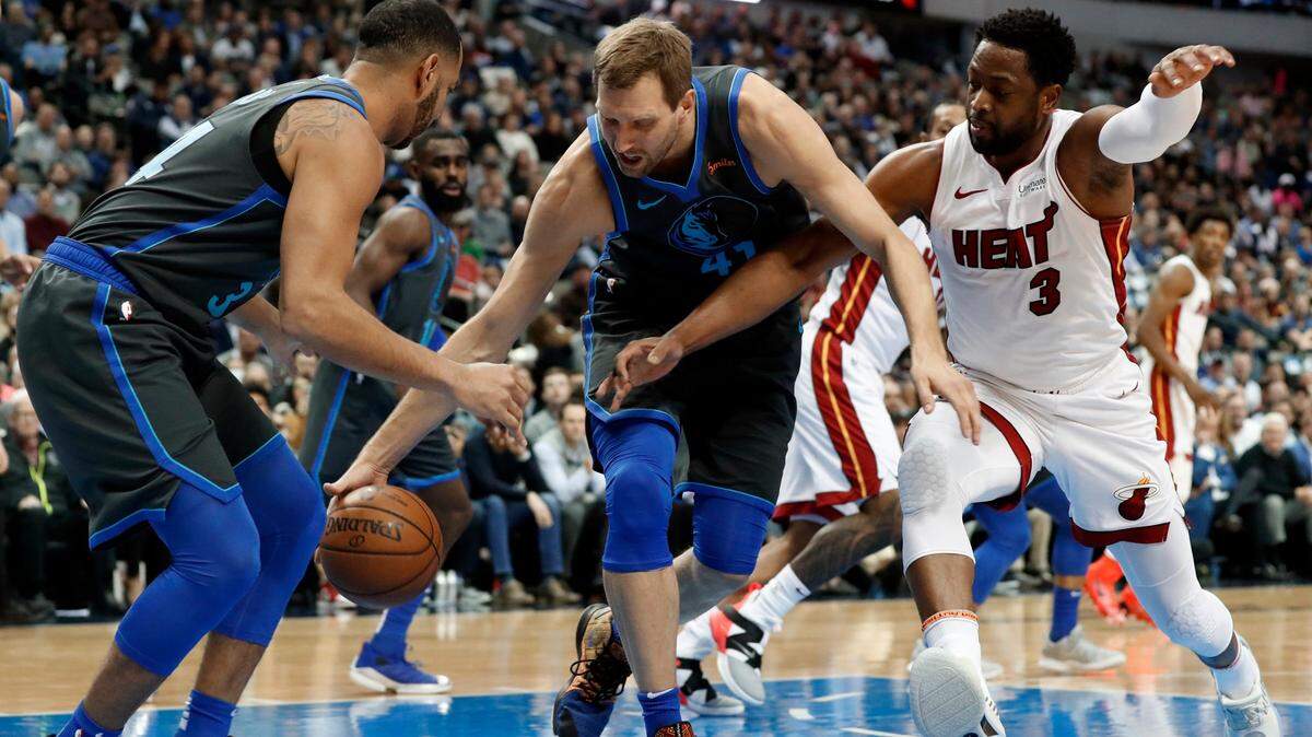 Dallas Mavericks guard Devin Harris, left, and forward Dirk Nowitzki, center, compete against Miami Heat guard Dwyane Wade (3) for control of a loose ball during the first half of an NBA basketball game in Dallas, Wednesday, Feb. 13, 2019. (AP Photo/Tony Gutierrez)