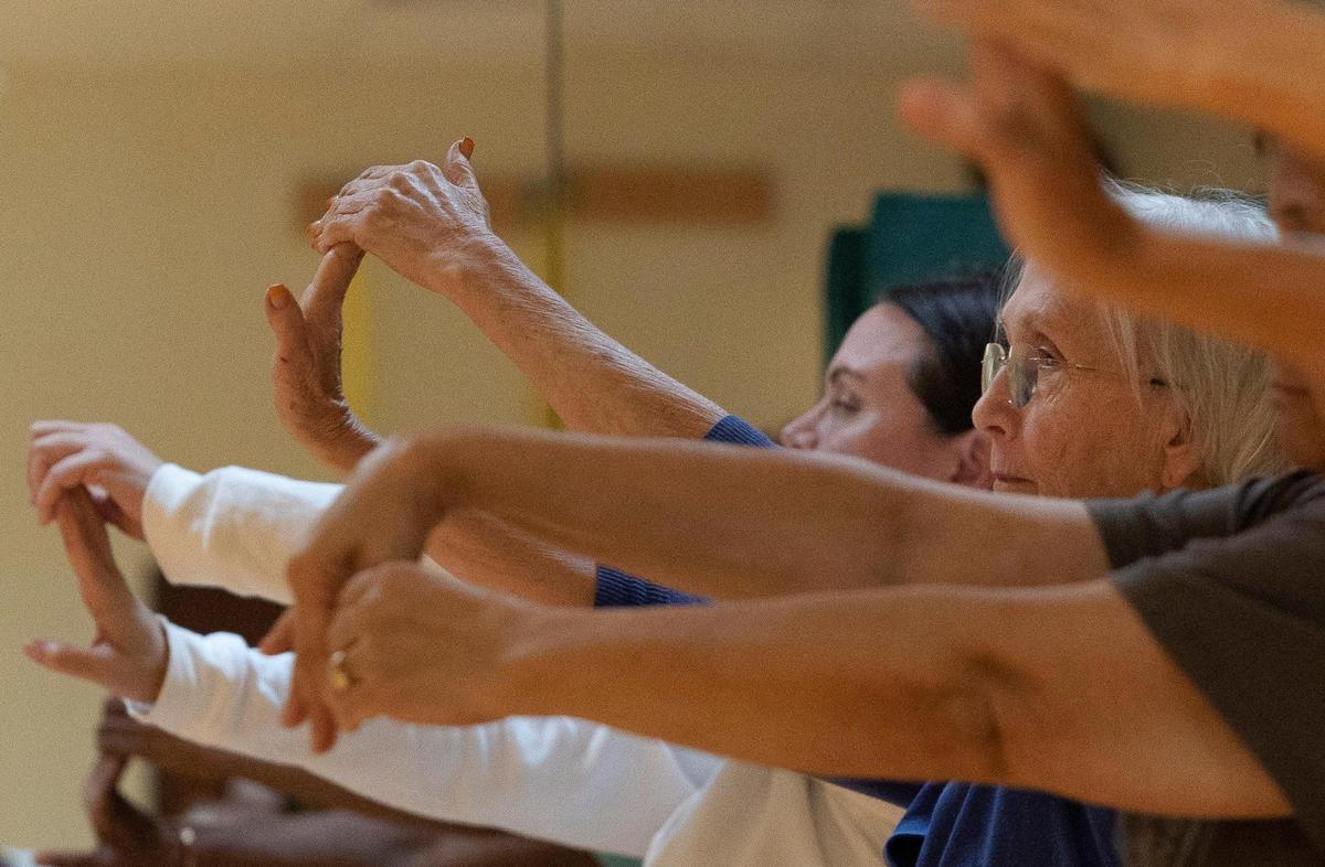 Pat Hobbs, en el centro, estira los brazos con otras pacientes durante una clase de yoga para pacientes con cáncer de mama, el miércoles 4 de octubre de 2023, en el Centro de Tratamiento Ambulatorio del Instituto de Rehabilitación Memorial en Hollywood. El yoga ayuda a los pacientes a lidiar con el estrés, la ansiedad y la depresión mediante la desaceleración y la atención plena.