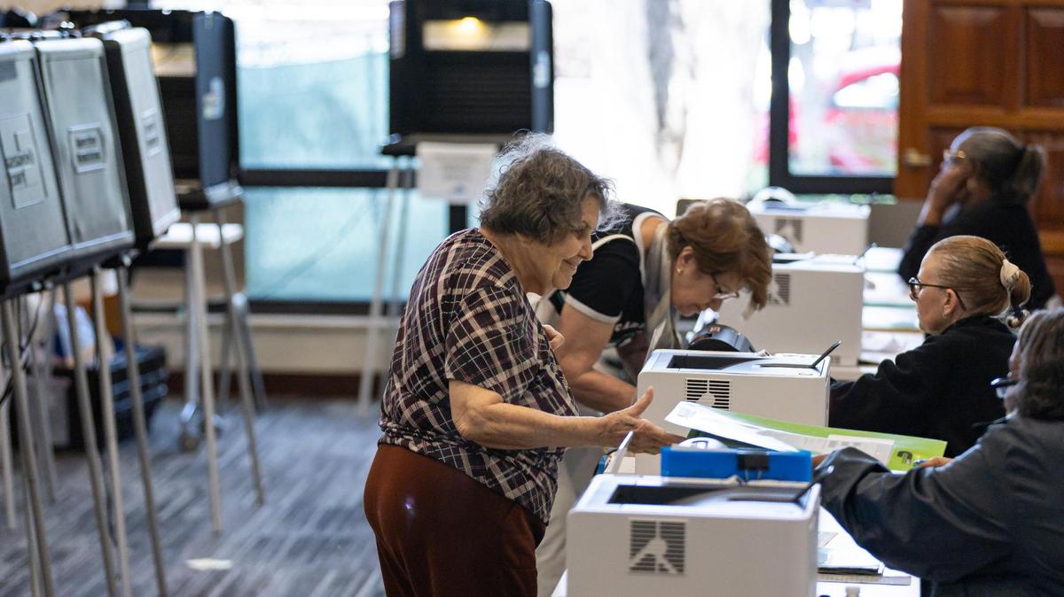 Carmen Sesin, center, receives her ballot during early in-person voting at the Coral Gables Library on Monday, March 4, 2024, in Coral Gables, Fla.