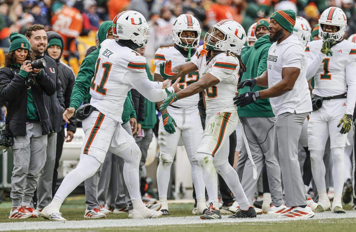 Miami Hurricanes wide receiver Malachi Toney (10) and quarterback Carson Beck (11) celebrate on the sidelines after Toney scores on a pass reception during the first half against the Pittsburgh Panthers during their NCAA football game at Acrisure Stadium in Pittsburgh, PA, on Saturday, November 29, 2025.