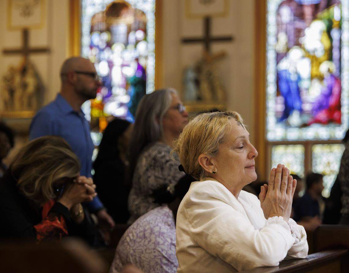 A woman prays after receiving ashes on her forehead during Ash Wednesday mass on Wednesday, Feb. 18, 2026, at Gesu Catholic Church in downtown Miami. The mass was fully packed with standing rom only at the back of the church. 