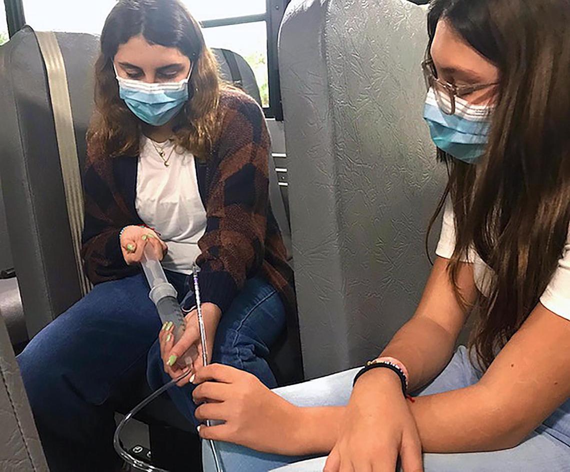 MAST Academy student Holly Thorpe, left, and her sister Lilly measure carbon dioxide levels inside an electric school bus. Thorpe’s science fair project showing hazardous emissions levels in Miami-Dade Schools’ diesel buses spurred the school board to seek funding to convert to an electric fleet.