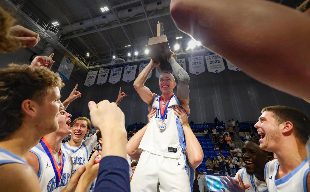 NSU Sharks Dallas Graziani (12) is lifted by teammate Alex Mangold (11) after winning the SSC championship game against the Florida Southern Mocs on Sunday, March 9, 2025, at the Rick Case Arena at Nova Southeastern University in Davie, Fla. NSU won 103-89.