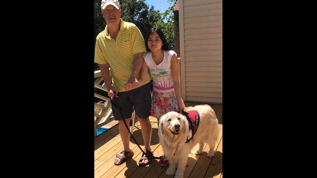 David W. Hemenway and his daughter Rebekah pose with her service dog, Bilbo Baggins, at their Virginia home.
