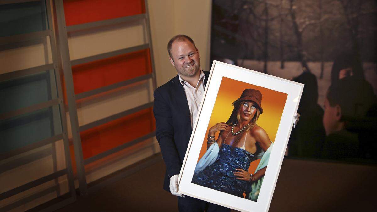 Miami Art Museum chief curator, Tobias Ostrander displays a piece of art from the recently donated Scholl Collection. The artwork he is holding is by artist Cindy Sherman, Untitled (suntan) from 2003 and is 33”x41”.