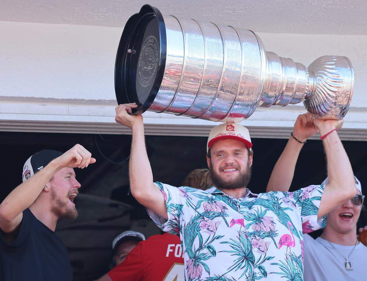 Panthers Captain Aleksander Barkov raises the Stanley Cup on the balcony of the Elbow Room in Fort Lauderdale the day after the Florida Panthers won the Stanley Cup Final for the second time on Wednesday, June 18, 2025.