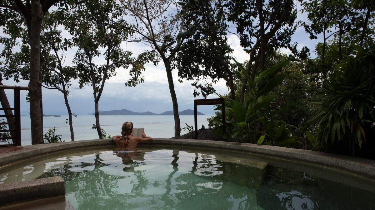 A woman reads a book in a splash pool overlooking the water at the Kamalaya Wellness Sanctuary June 18, 2012.