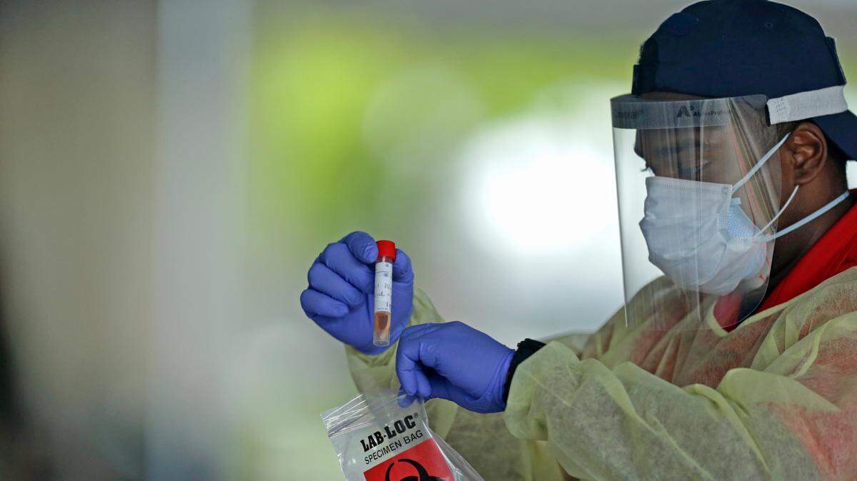 An American Medical Response health worker holds a swab tests from citizens after being tested at the COVID-19 drive-thru testing center at Holiday Park located at 1150 G. Harold Martin Drive in Fort Lauderdale as the coronavirus pandemic continues on Thursday, April 30, 2020.