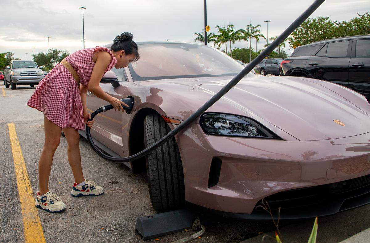 A driver plugs her pink Porsche Taycan into an electric vehicle charging port in the Walmart parking lot in Hialeah last year. 