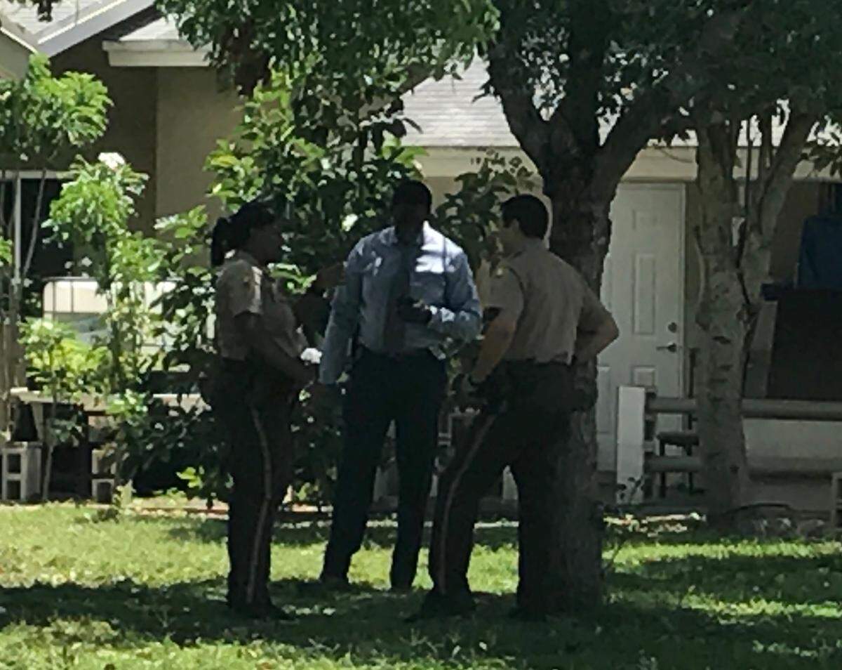 Miami-Dade police officers talk on Thursday, May 23, behind a house on Southwest 126th Court where Kerica Nelson, 21, lived. She was shot and killed Wednesday, and her body was found in a park in the Homestead subdivision of Verde Gardens.