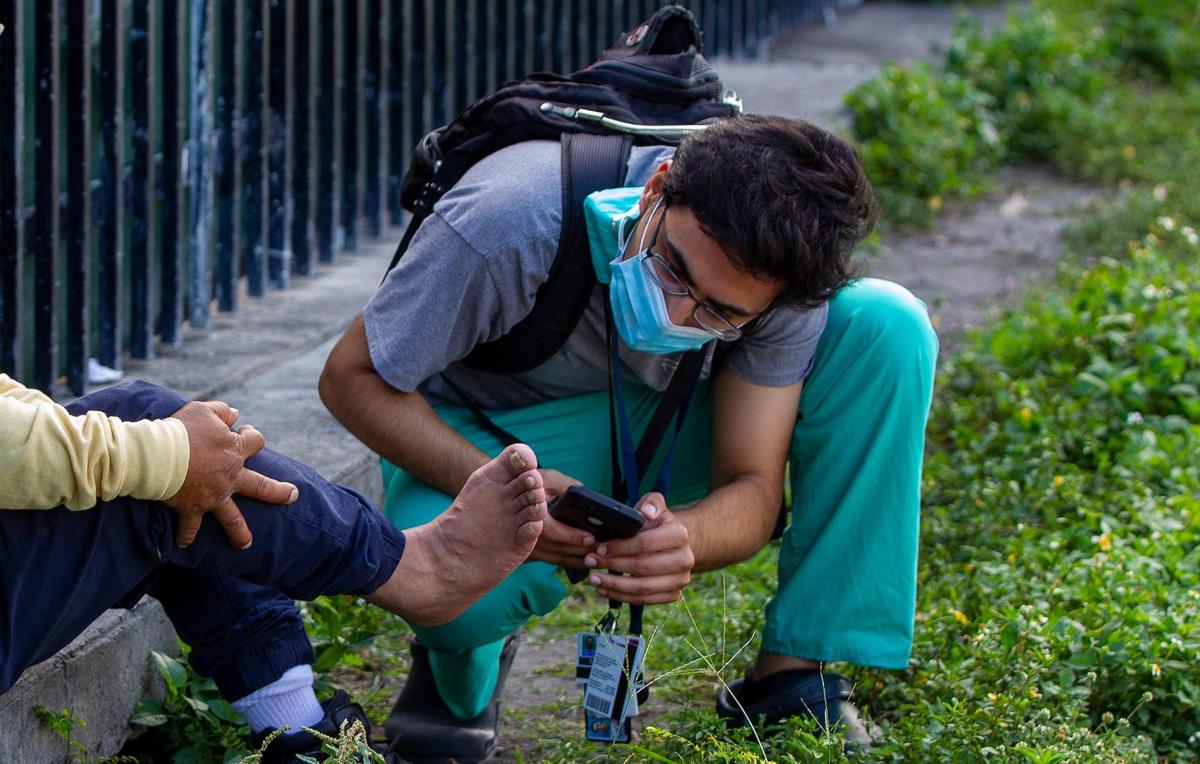 University of Miami medical student Taha Rasul, a member of the Miami Street Medicine team, checks the foot of a man during their weekly rounds along Northwest 17th Street in Miami on March 5, 2022. Miami Street Medicine is a mobile clinic launched by Dan Bergholz, a third-year student at the Miller School of Medicine at UM, in which volunteer medical school students treat Miami’s homeless community on the streets.