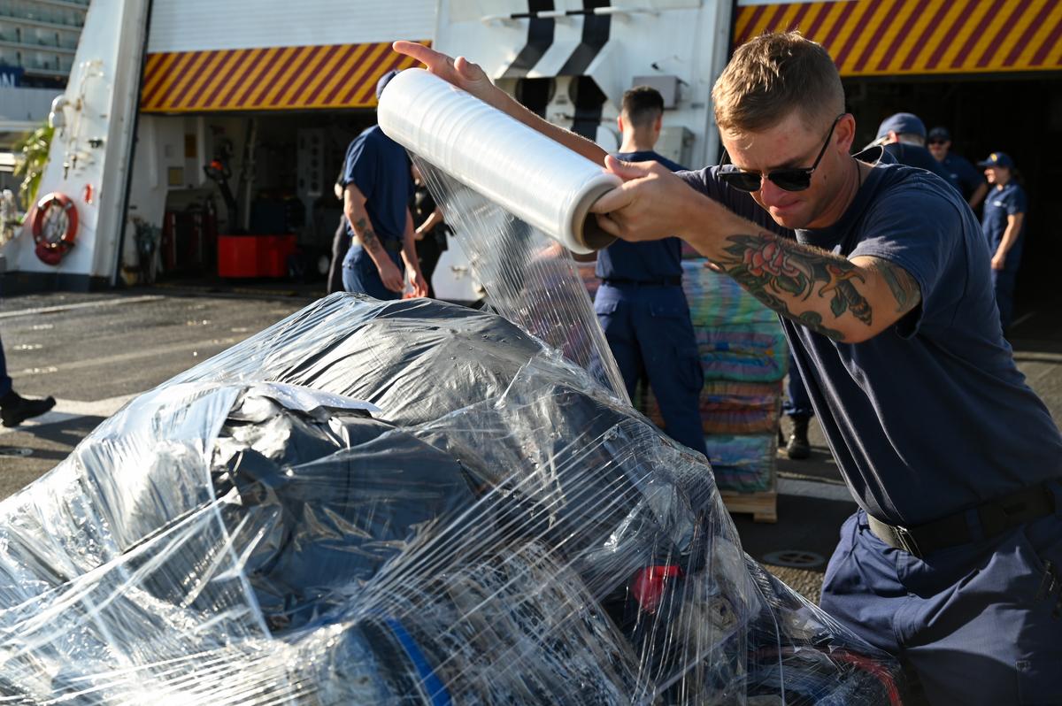 A U.S. Coast Guard Cutter Hamilton crew member plastic wraps drugs during an offload of approximately 76,140 pounds of illegal narcotics at Port Everglades Monday, Aug. 25, 2025.