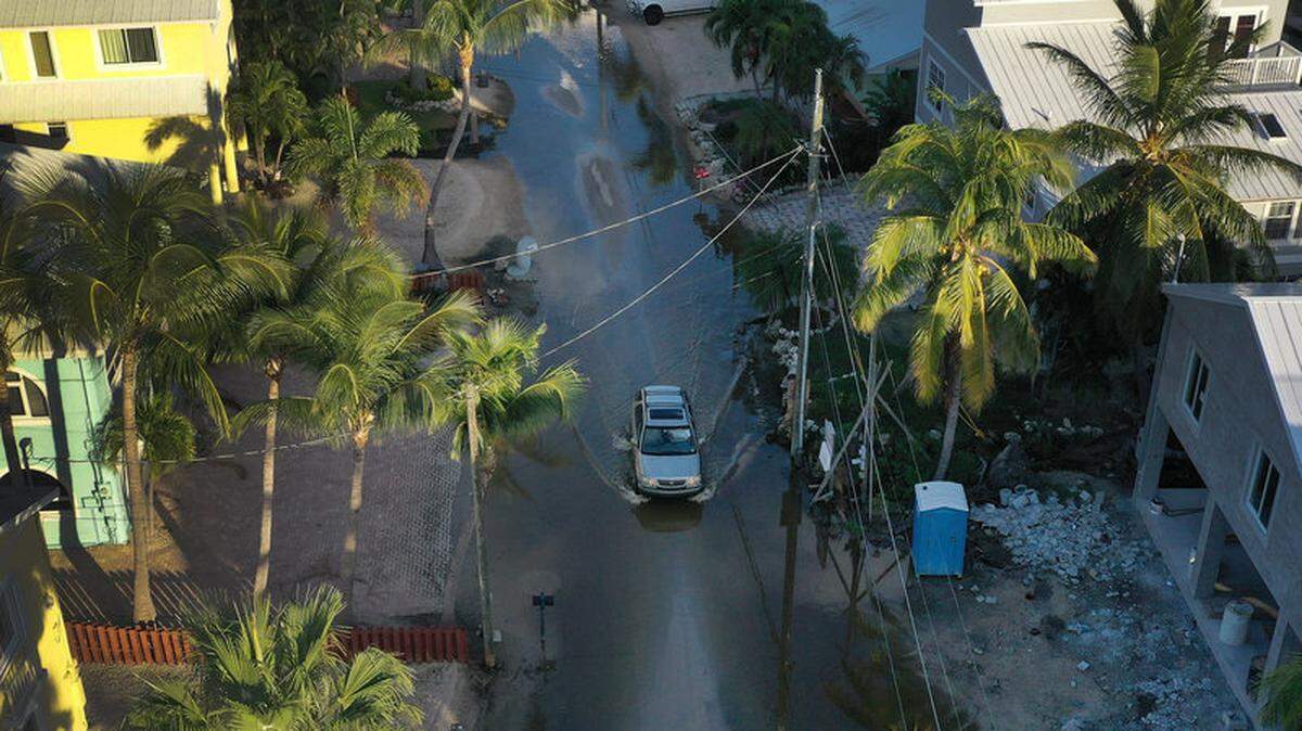 A car drives through a street flooded with ocean water in Key Largo.
