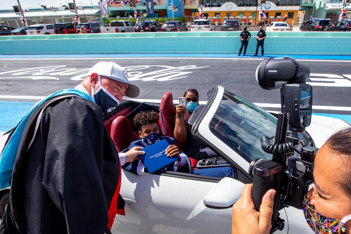 Principal David Pugh poses for a photo with a senior after handing him his diploma on the race track during the Christopher Columbus High School senior graduation ceremony at Homestead-Miami Speedway, in Homestead, Florida on Saturday, June 20, 2020.