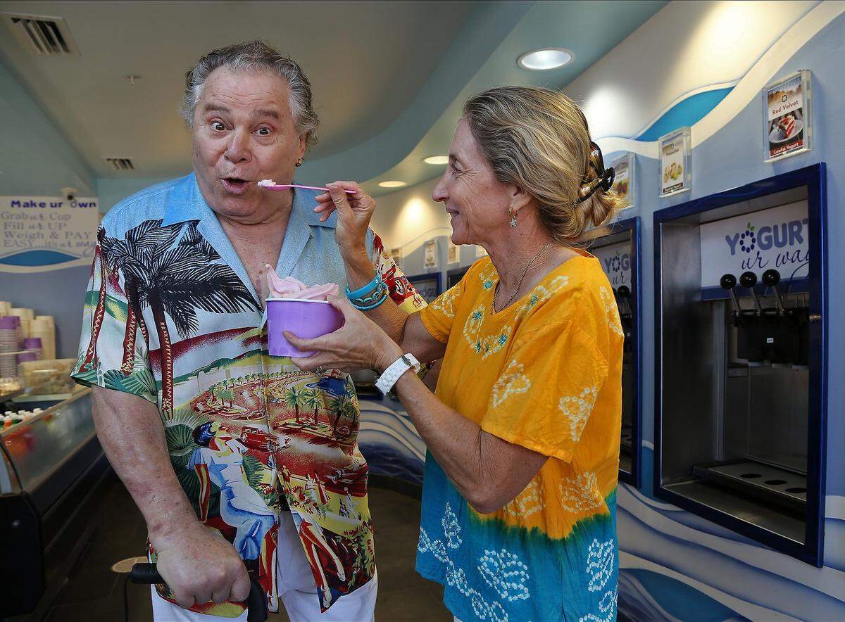 Actor Art Metrano, left, reacts prior to sampling his own yogurt from his wife, Jamie, right, at his Hollywood Beach store on Tuesday, January 14, 2012.