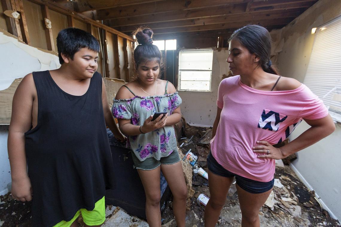 From left to right: Tony Perez, 13, Carolina Vega, 14, and Rosa Perez, 34, stand inside the remains of their home in a public housing complex in Panama City, Florida on Friday, October 19, 2018. Hurricane Michael devastated the Florida Panhandle, leaving tens of thousands without food, power or shelter.