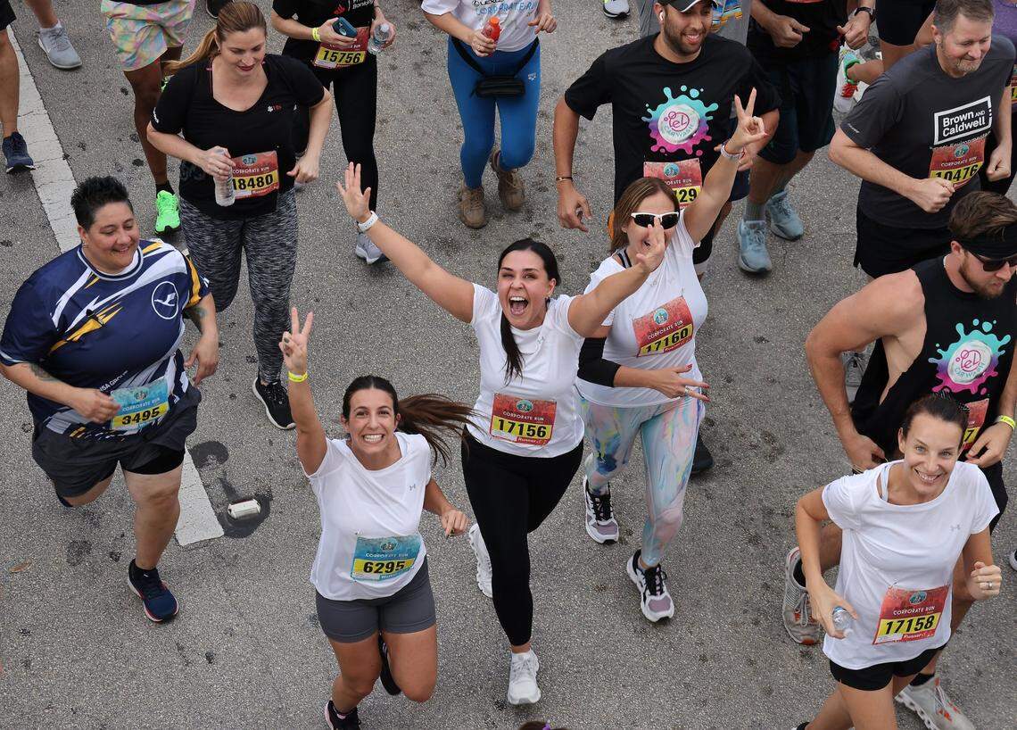 Runners react to the camera at the start of the 3.1 mile race in downtown Miami on April 25, 2024, during the Lexus Corporate Run in downtown Miami.