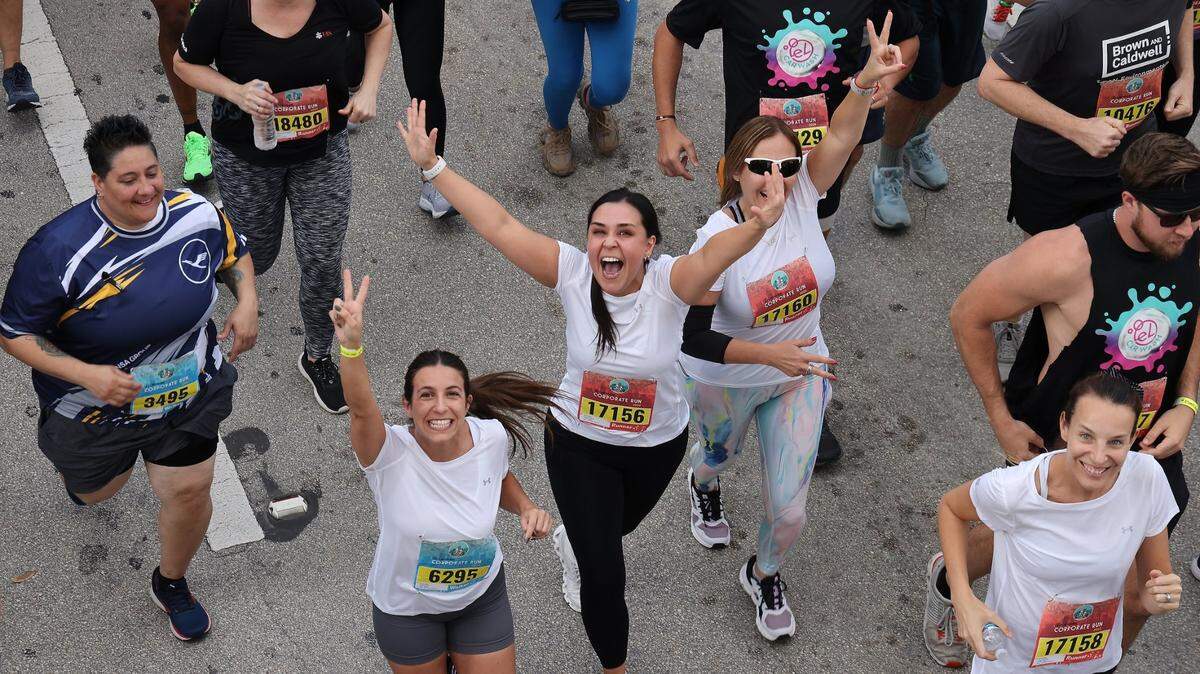 Runners react to the camera at the start of the 3.1 mile race in downtown Miami on April 25, 2024, during the Lexus Corporate Run in downtown Miami.