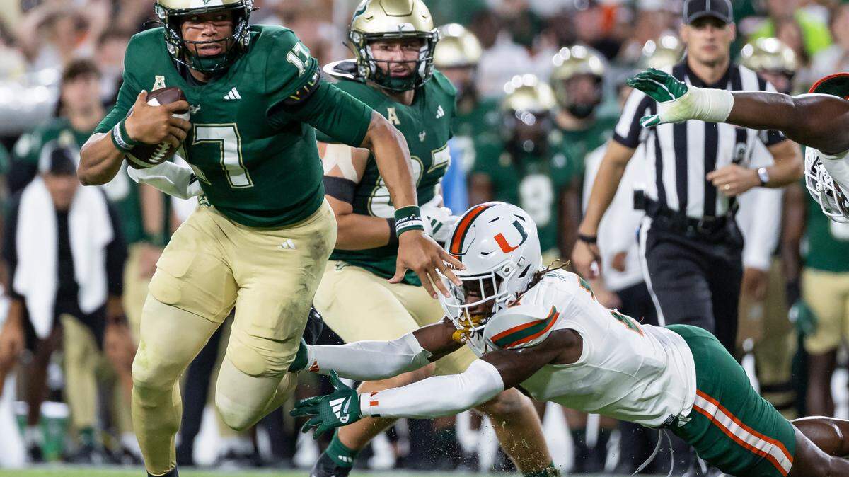 South Florida Bulls quarterback Byrum Brown (17) makes his way past Miami Hurricanes defensive back Jaden Harris (7) in the first half of their NCAA college football game at the Raymond James Stadium on Saturday, Sept. 21, 2024, in Tampa, Fla.