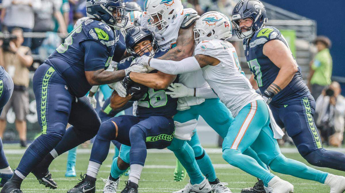 Miami Dolphins defensive tackle Da’Shawn Hand (90), Miami Dolphins safety Jevon Holland (8) and teammates take down Seattle Seahawks running back Zach Charbonnet (26) in the first half during an NFL game at Lumen Field in Seattle, Washington on Sunday, September 22, 2024.