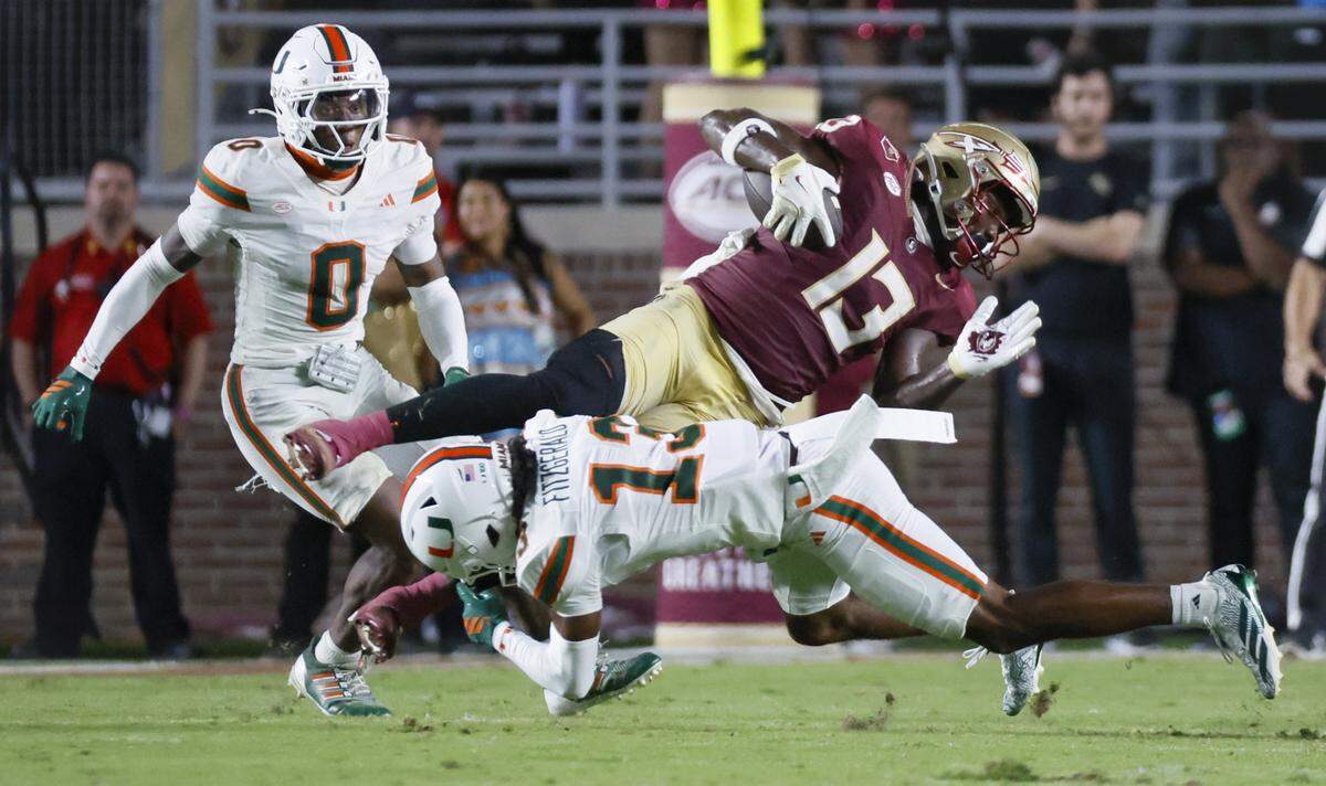 Miami Hurricanes defensive back Bryce Fitzgerald (13) takes down Florida State Seminoles tight end Randy Pittman Jr. (13) during the second half of their NCAA game at Doak Campbell Stadium in Tallahassee, Florida, on Saturday, October 4, 2025.
