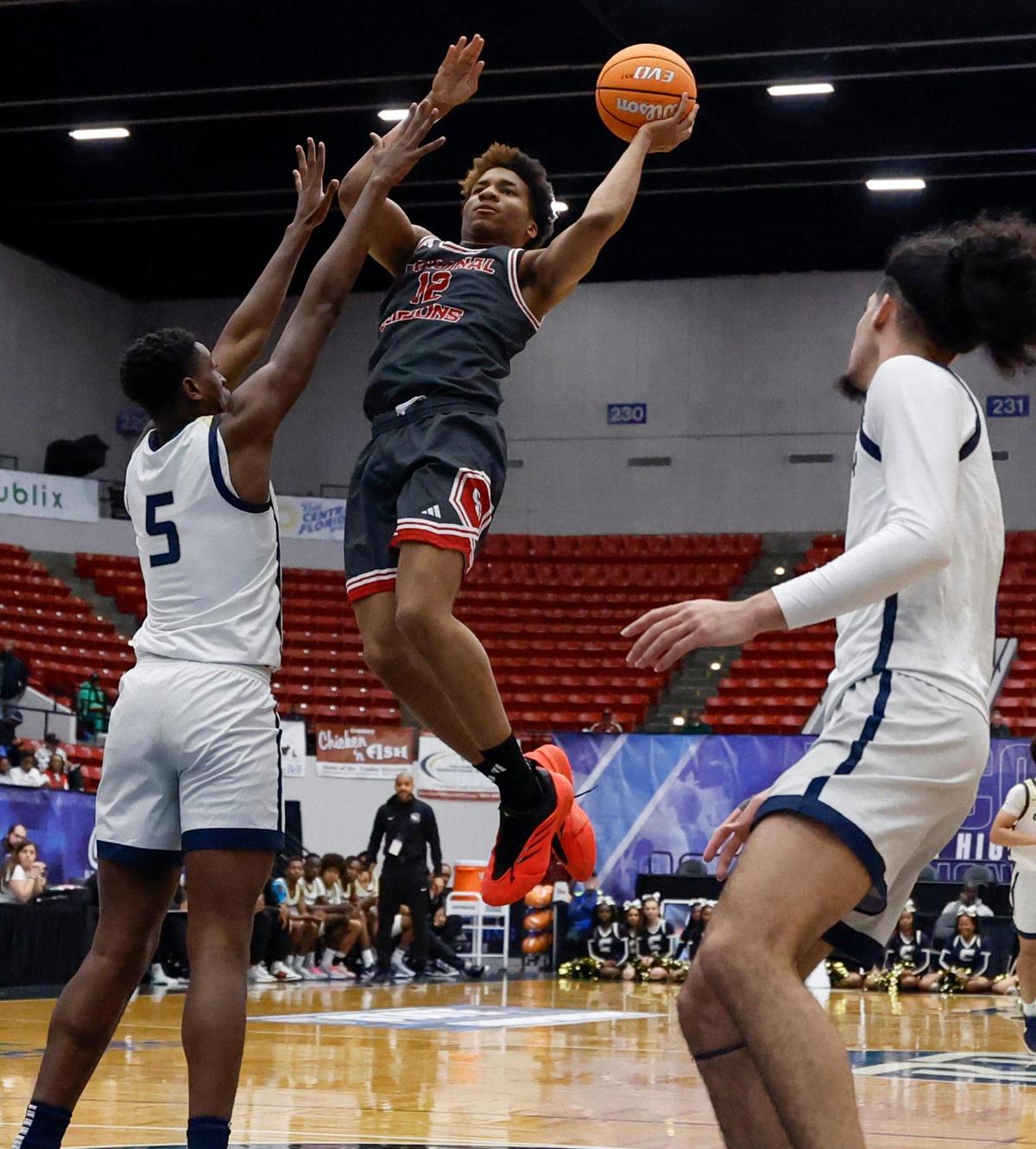 Cardinal Gibbons Justus Herbert (12) attempts to score as Calvary Christian Academy’s KJ Ambrose (5) defends in the second half during boys 3A basketball semifinal game of the Florida High School State Championships at the RP Funding Center in Lakeland, Florida on Friday, February 28, 2025.