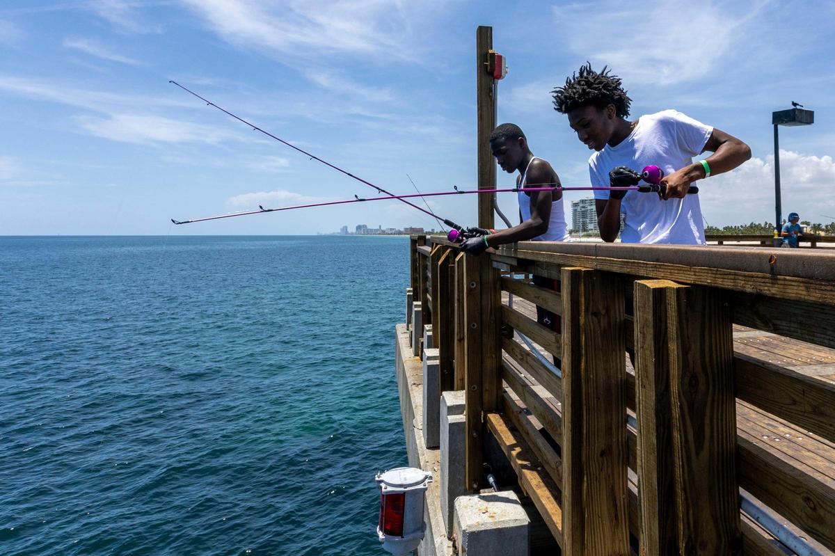 Campers Jatari Johnson and Ethan McNeal fish from the pier during a Root Collectives summer camp field trip at Dania Beach Pier.