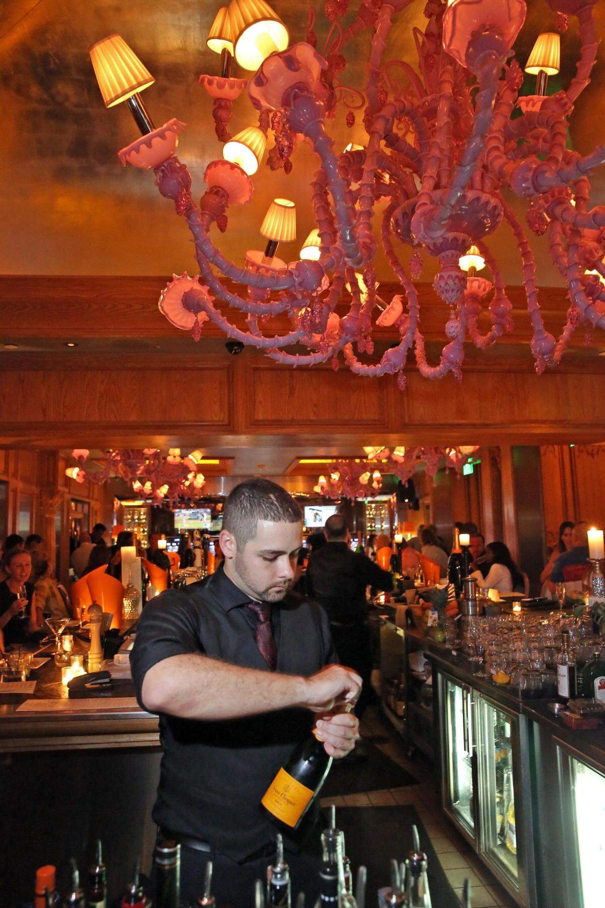 Forge bartender, Jesse Moreno, uncorks a bottle of Veuve Clicquot on a busy Friday night, August 7, 2015.