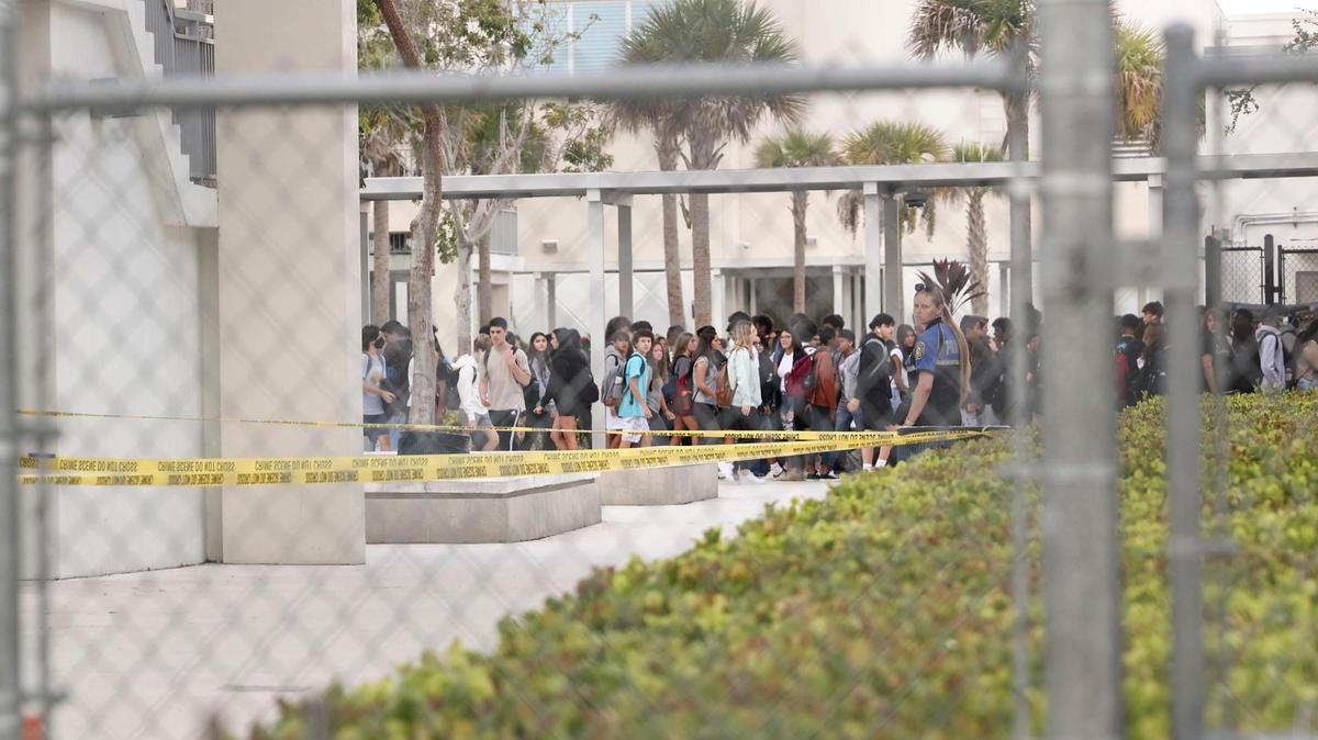 Students walk to class while glancing at the yellow police caution tape at Miami Palmetto High School on Tuesday, Aug. 23, 2022, in Pinecrest, Florida. A student with ‘traumatic injuries’ was airlifted from the school shortly after the school day began due to a possible fall, according to Miami-Dade Fire Rescue. School district officials have not identified the student, nor has Fire Rescue.
