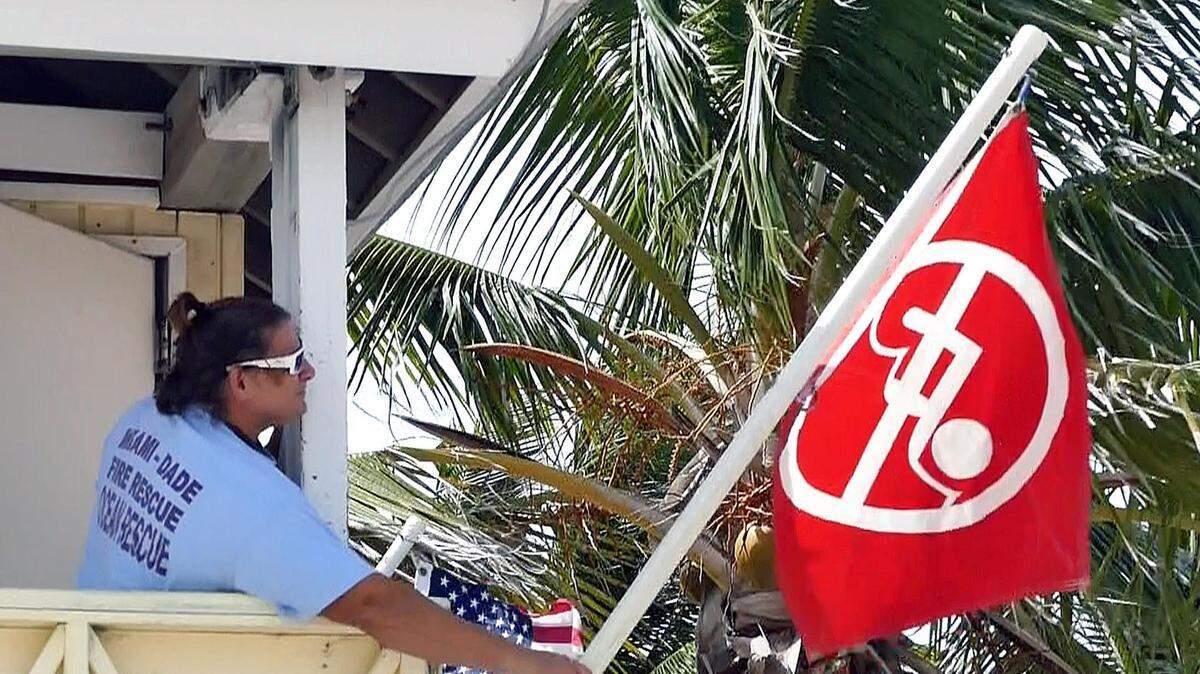 FILE PHOTO: A Miami-Dade Ocean Rescue lifeguard placed a beach closed red flag at North Crandon Beach in Key Biscayne on Aug. 30, 2018.  The beach was one of many closed for periods of time in that summer due to swimming advisories over bacteria in the waters.