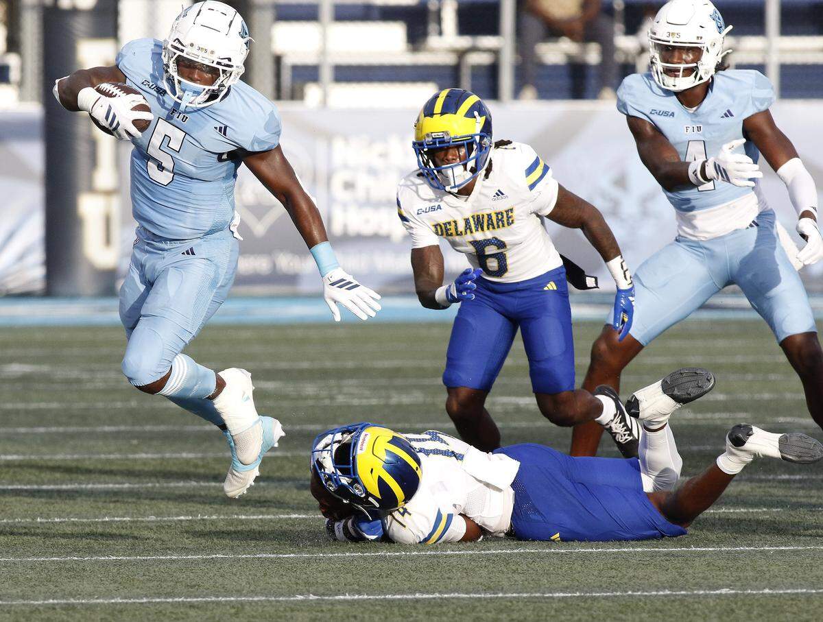 FIU Panthers running back Kejon Owens (5) evades a tackle by Delaware Fightin' Blue Hens defenders during football game on Saturday, September 20, 2025 at FIU Pitbull Stadium in Miami.  Andrew Uloza / for Miami Herald