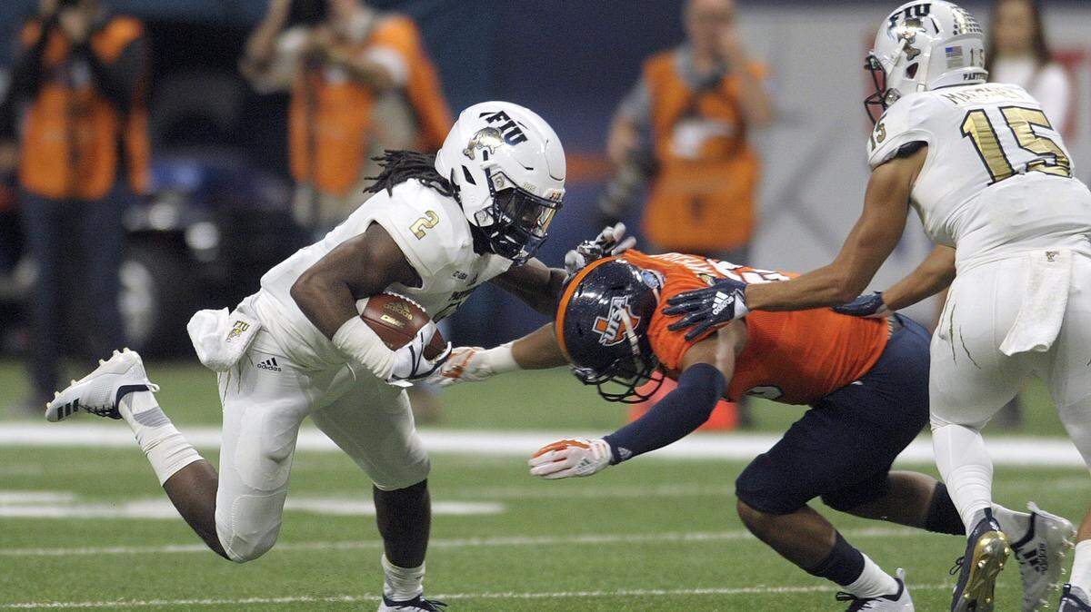 FIU running back Anthony Jones runs for yardage against UTSA defender Cassius Grady as Austin Maloney (15) attempts to block.