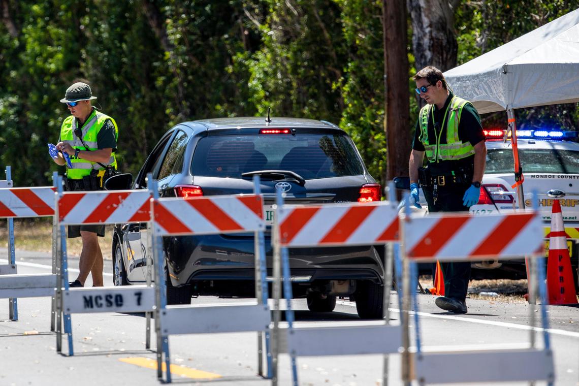 Monroe County sergeant James Hager and deputy Shaun Lones instruct drivers at a checkpoint erected on County Road 905 in order to curb the novel coronavirus pandemic, in Key Largo, Florida on Sunday, March 29, 2020.