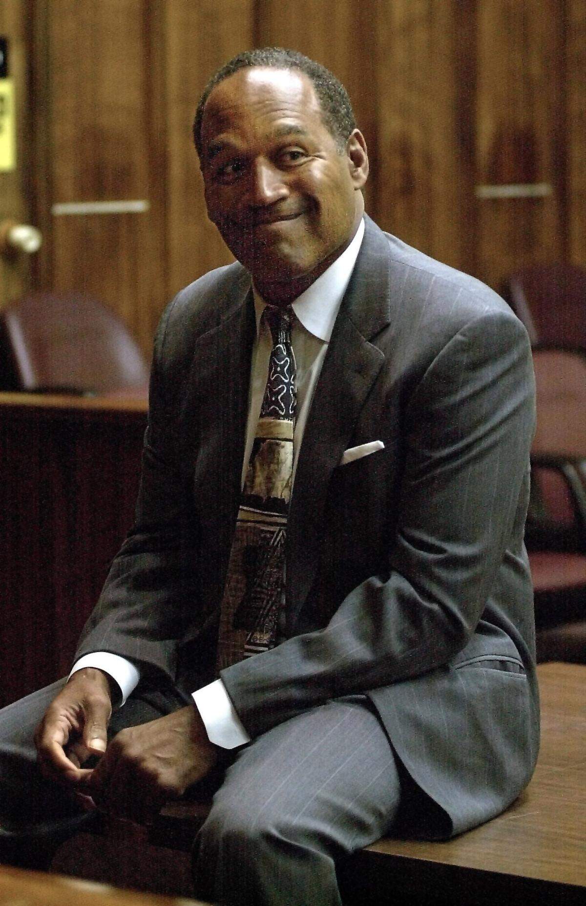 La ex estrella de la NFL O.J. Simpson espera sentado el comienzo del juicio durante la segunda jornada de su juicio por violencia vial en Miami, el 22 de octubre de 2001. Simpson, que fue absuelto en 1995 de asesinar a su ex esposa y a un amigo de esta, estaba siendo juzgado por un delito grave de robo de vehículo y un delito menor de lesiones.