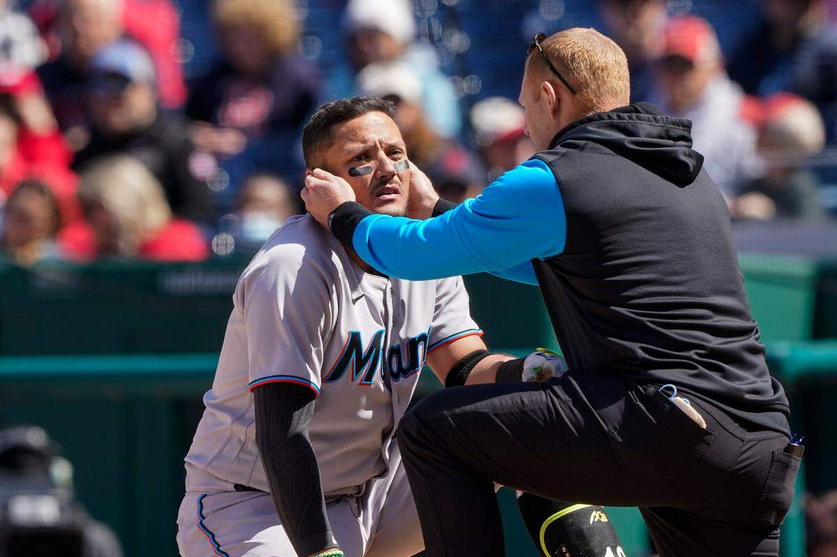 Miami Marlins’ Miguel Rojas, left, is checked after he was hit by pitch during the seventh inning of a baseball game against the Washington Nationals at Nationals Park, Thursday, April 28, 2022, in Washington. (AP Photo/Alex Brandon)