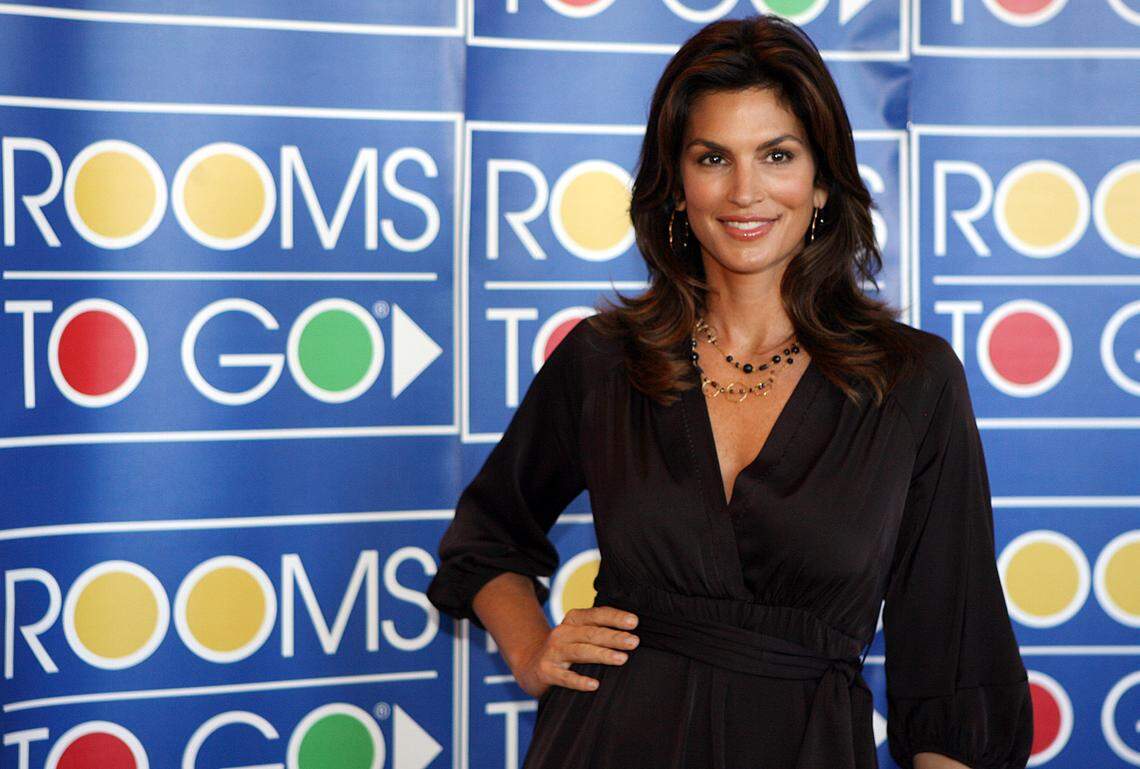 In this file photo from Jan. 11, 2008, Model Cindy Crawford models for photographers at the Rooms to Go store in Kendall across from Dadeland Mall during a visit to Miami to do some PR for the furniture store.